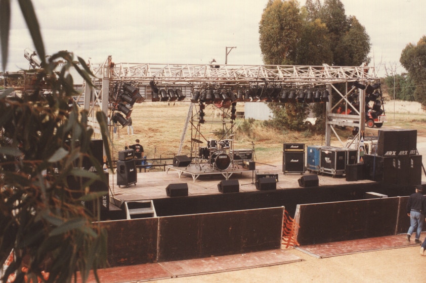 Shot of stage with large lighting grid above in a browned off paddock.