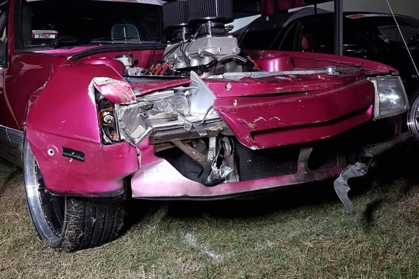 A damaged front end of a pink car.