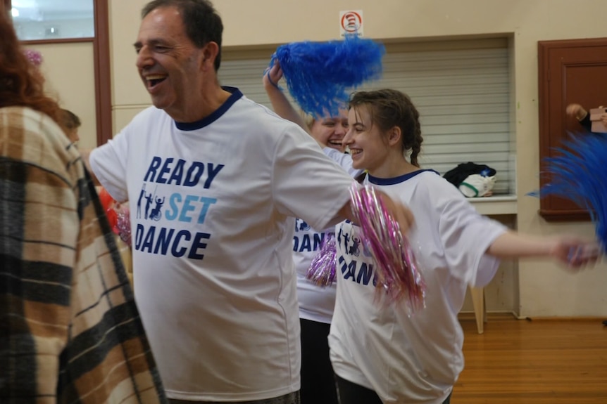 Two people smiling and waving streamers as they dance.