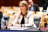 Optus CEO Kelly Bayer Rosmarin sits at a desk in front of a microphone at a Senate inquiry.