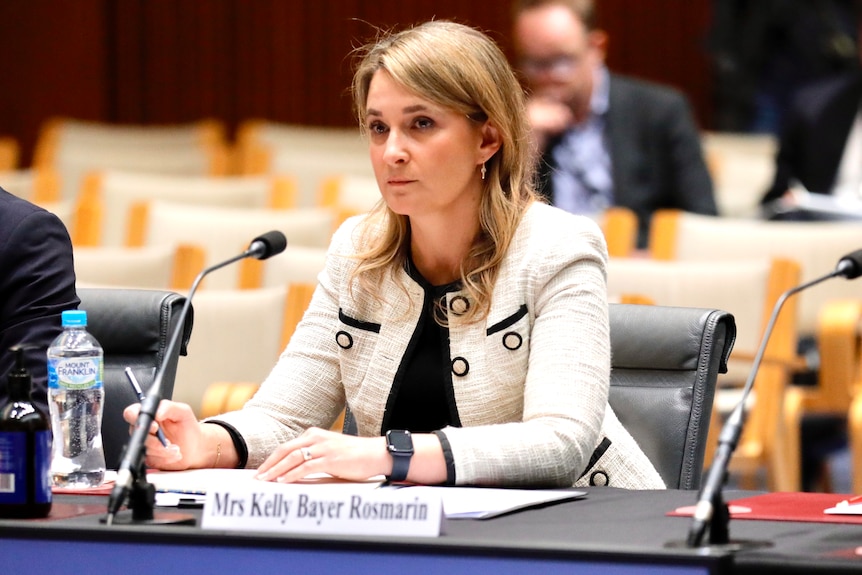 Optus CEO Kelly Bayer Rosmarin sits at a desk in front of a microphone at a Senate inquiry.
