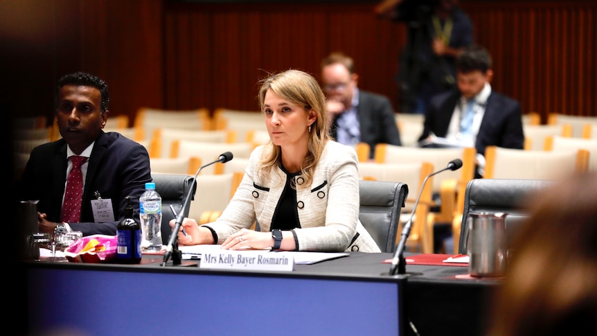 Optus CEO Kelly Bayer Rosmarin sits at a desk in front of a microphone at a Senate inquiry.