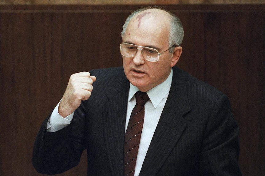 Michaił Gorbaczow w garniturze i zaciskając pięść podczas przemówienia