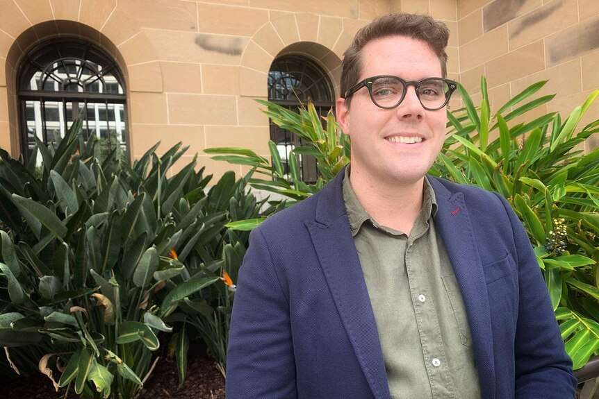 Le conseiller Ryan Murphy sourit devant l'hôtel de ville de Brisbane.