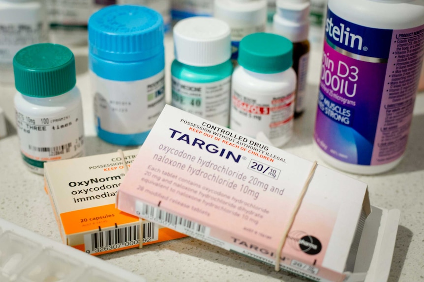 Packets of prescription only opioid pain kills are shown among other medications taken by a person experiencing chronic pain.