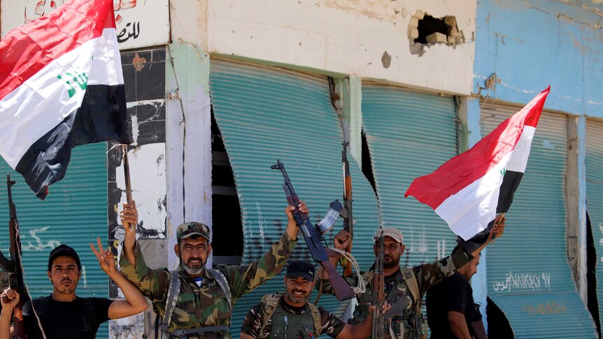 Iraqi shi'ite fighters hold Iraqi flags in Garma