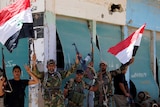 Iraqi shi'ite fighters hold Iraqi flags in Garma