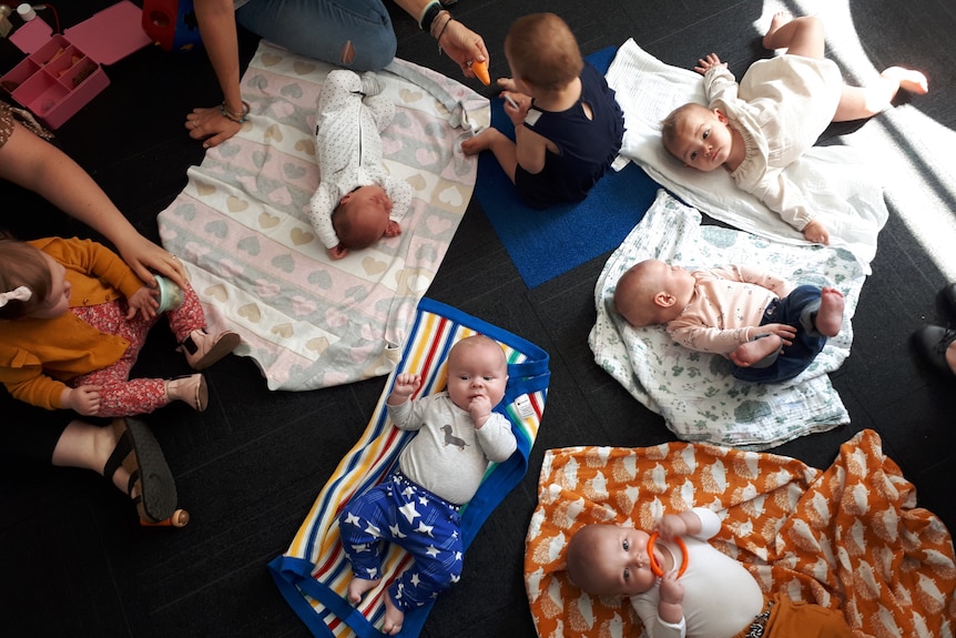 Babies are lying on the floor on different blankets in a circle
