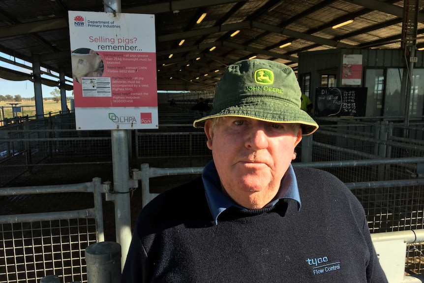 A man stands in front of a saleyard