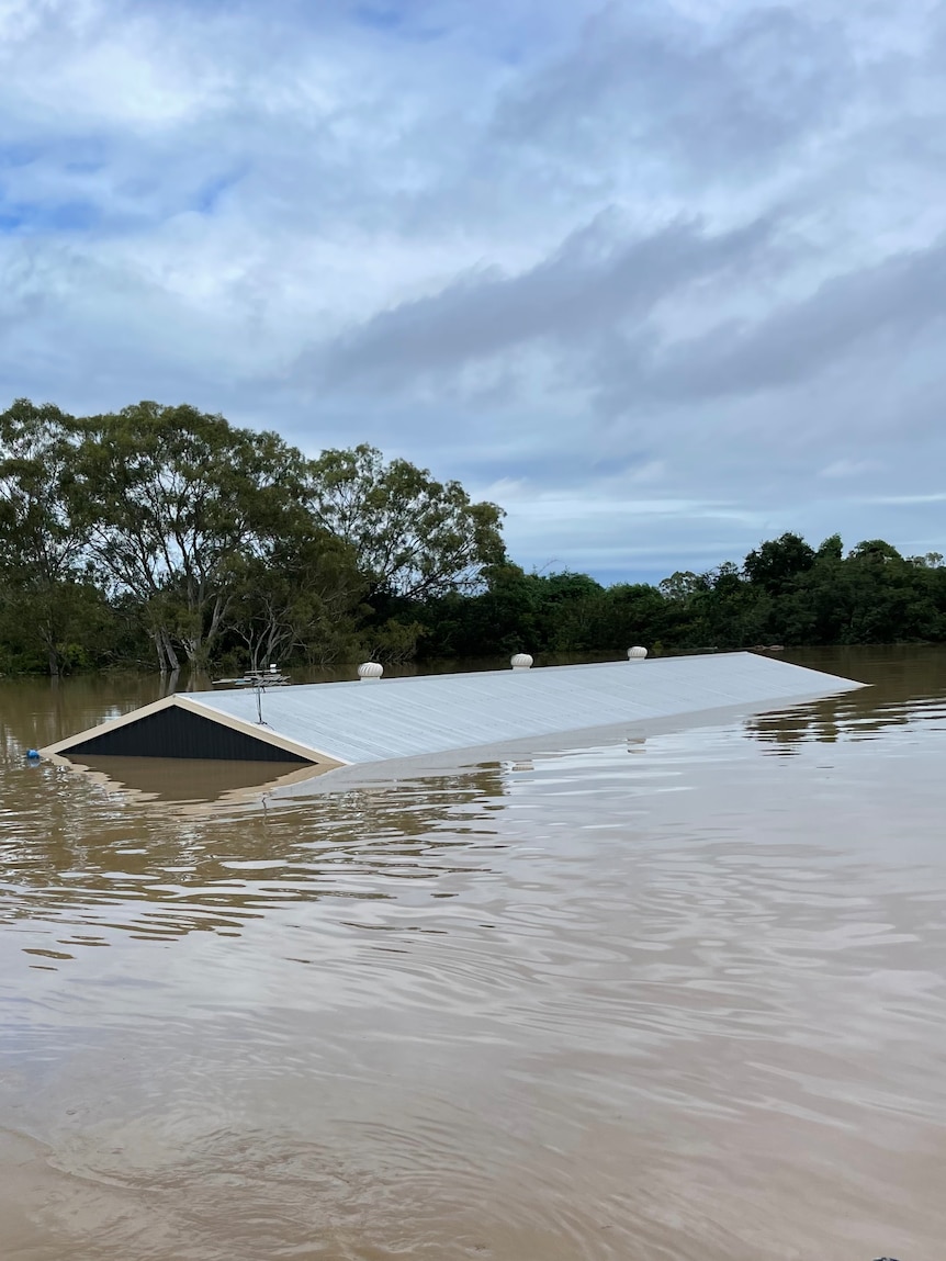 A workshop inundated by flood waters with only a partial roof visible.