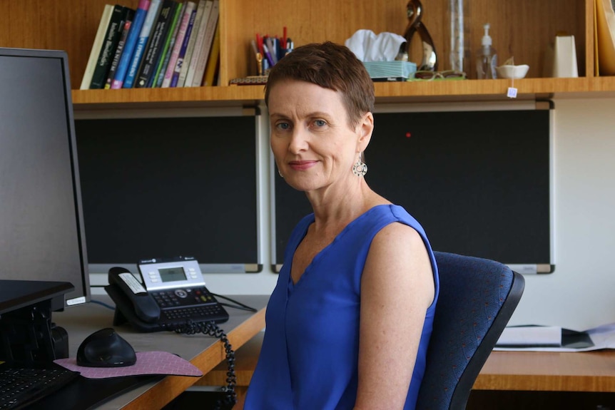 A woman sits at a desk.