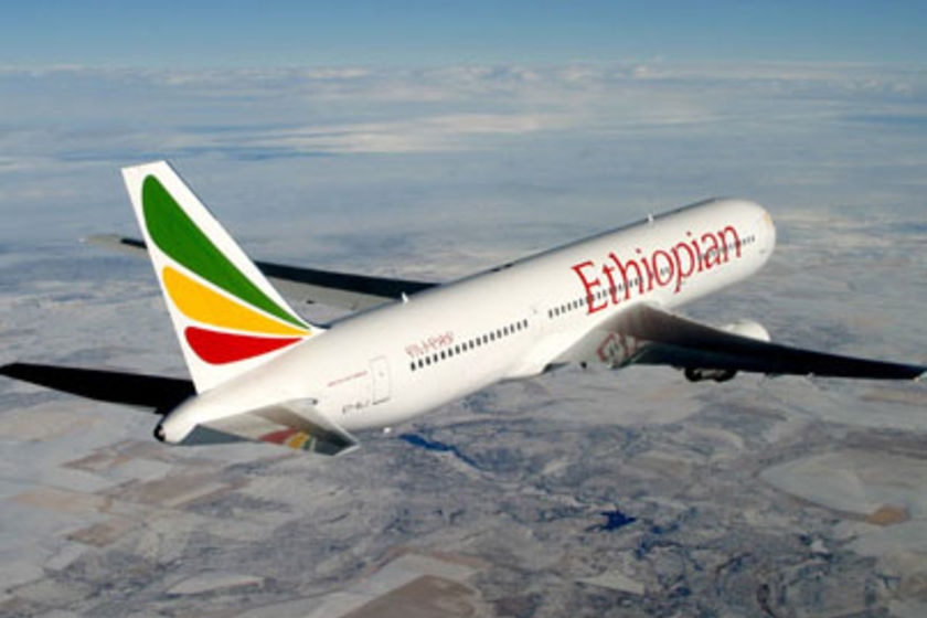 A plane with Ethiopian Airlines branding flies through clouds.