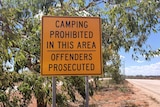 A camping prohibited sign in yellow at truck bay