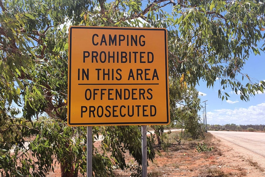 A camping prohibited sign in yellow at truck bay