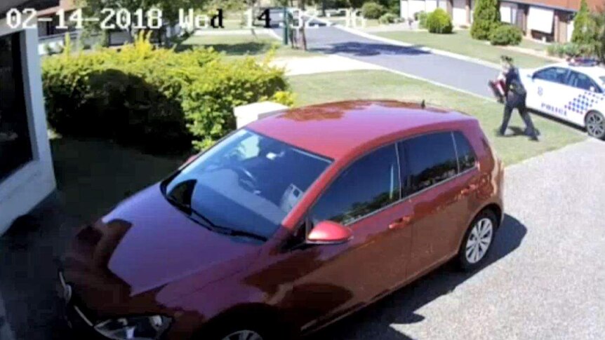 CCTV image of a female police officer running from a police car to a house