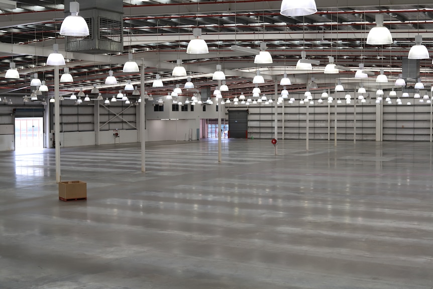 The interior of an empty warehouse with lights hanging from the ceiling.