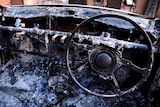 The burnt-out remains of a car and houses