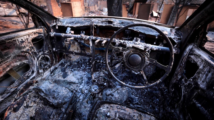 The burnt-out remains of a car and houses