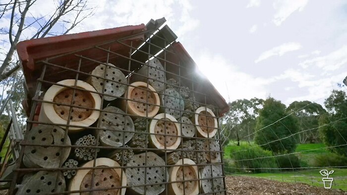 Logs with holes in the centre in a caged enclosure with a roof.
