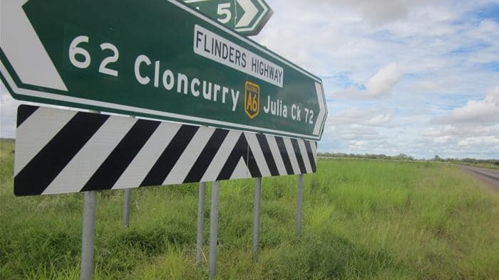 A road sign on the side of a country highway indicating the way to Cloncurry and Julia Creek.