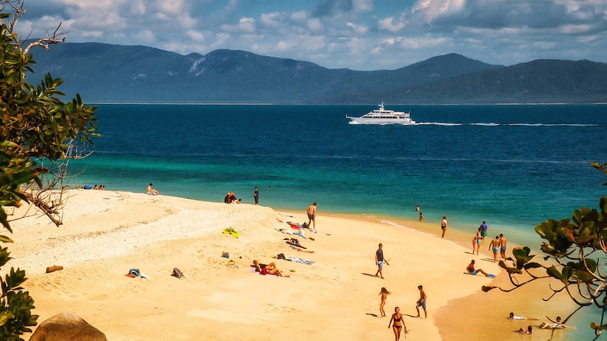 A boat goes past a beach.