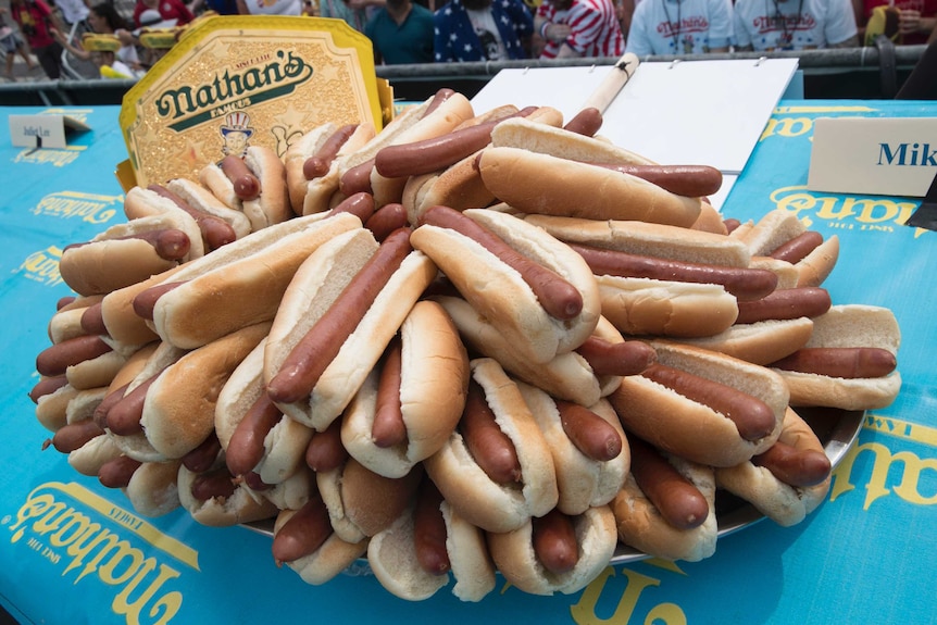 Huge pile of hot dogs sits in front of championship belt