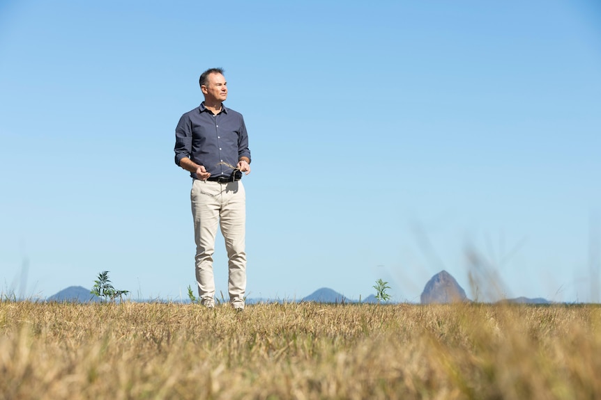 Man standing on grassy plain with mountain in background