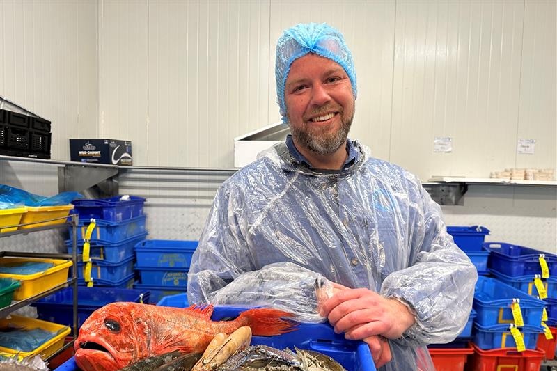 Image of a man standing in front of fish.