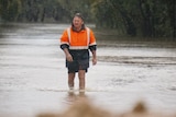 A man walks through floodwater in the rain.