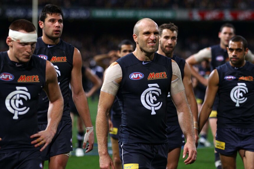 Chris Judd leads his players from the field