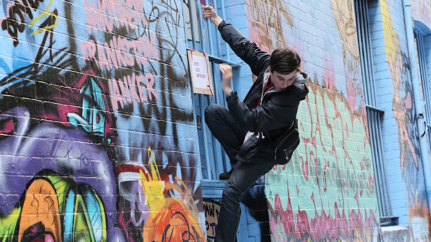 An artist climbs a wall in Hosier Lane, Melbourne