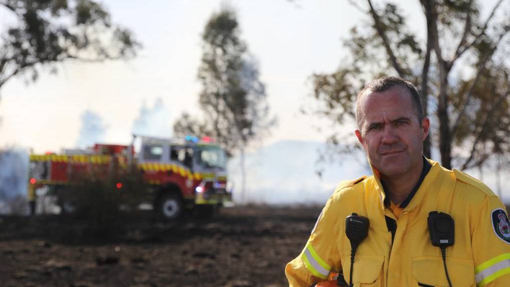 Bradley Stewart no campo em frente a um caminhão de bombeiros. 