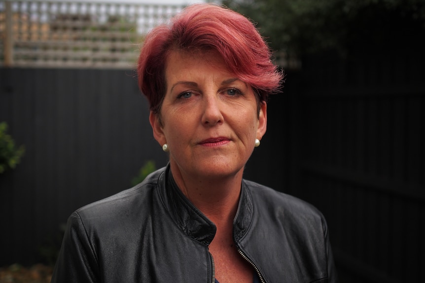 A woman with red hair wearing a leather jacket.