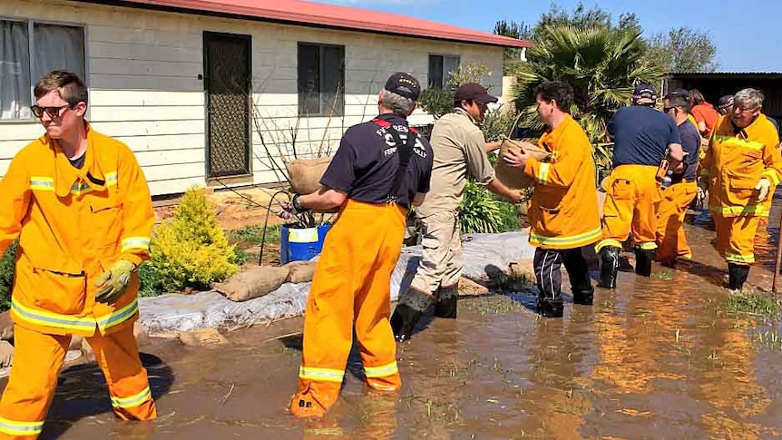 CFA volunteers sandbag a house.