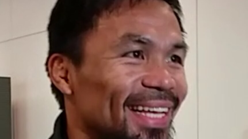 Manny Pacquiao smiles, speaks into two microphones