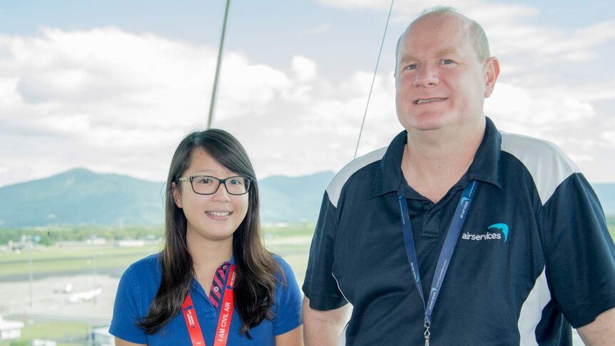 Amanda Siu and Shane Higgins stand in front of the vast windows at the Cairns Airport air traffic control tower.
