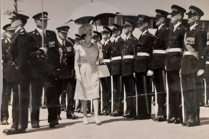 A black and white photo of a young Queen Elizabeth II inspecting a row of royal guards