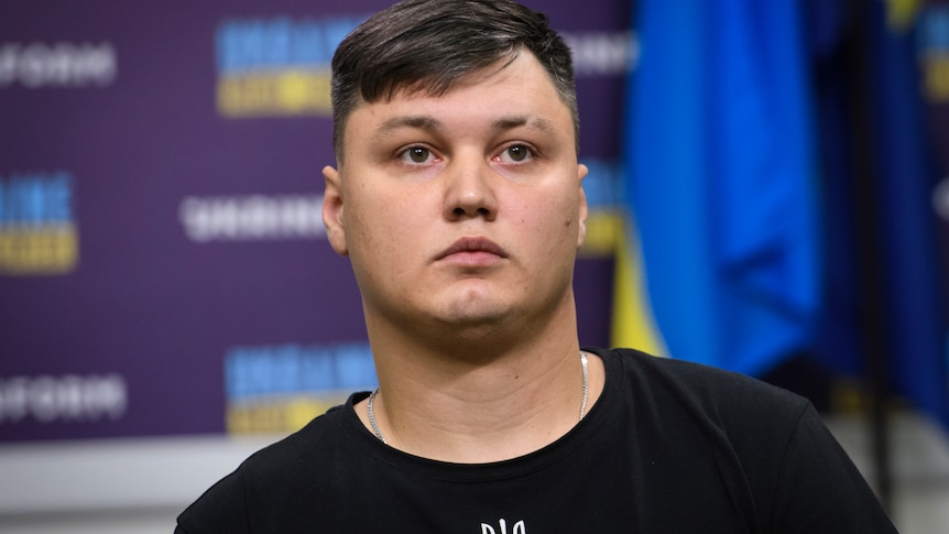 A Russian man with brown hair, round face and plain black t shirt in a press conference