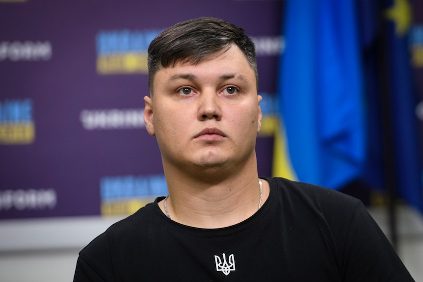 A Russian man with brown hair, round face and plain black t shirt in a press conference