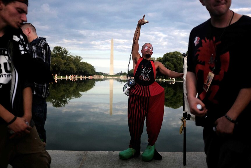 A man in oversized pants poses at the top of the reflecting pool.