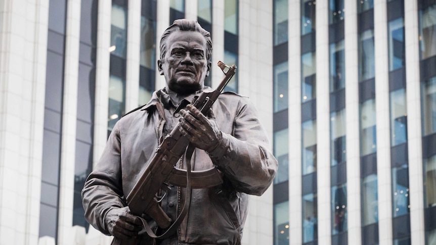 A monument of Russian firearm designer Mikhail Kalashnikov dressed in a bomber jacket and clutching an AK-47 in both hands.