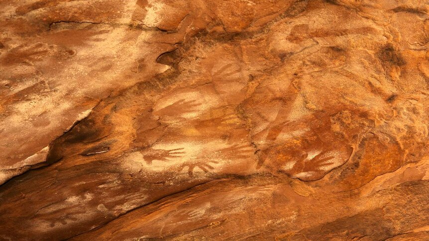 A sandstone rockface with evidence of Indigenous art including hand stencils