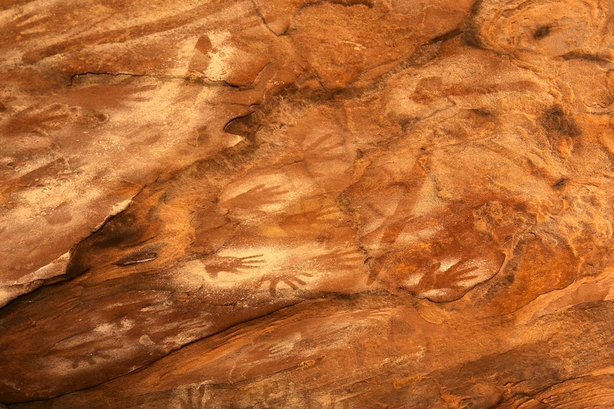 A sandstone rockface with evidence of Indigenous art including hand stencils