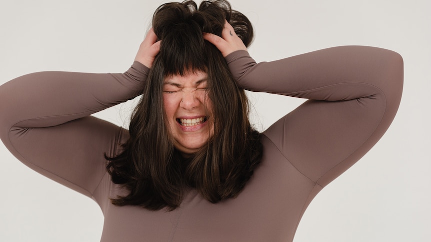 Woman clutching her brown hair and looking frustrared.