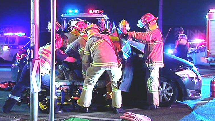 At night, at a major intersection, emergency services crews deal with a car crash.