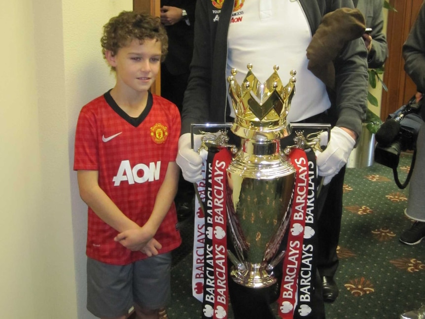 A Manchester United fan gets a rare photo with the English Premier League Trophy during its visit to Newcastle.