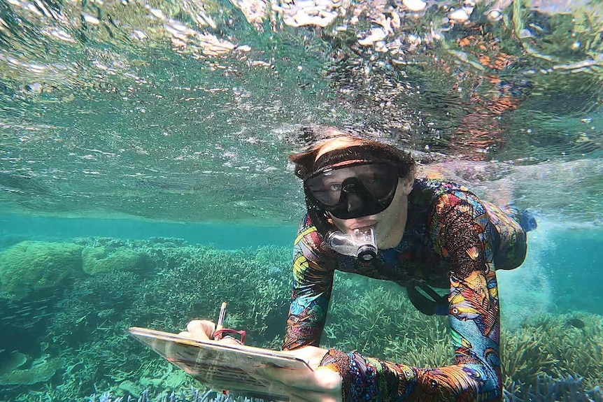 Arlian Ecker underwater with a clipboard at the Great Barrier Reef