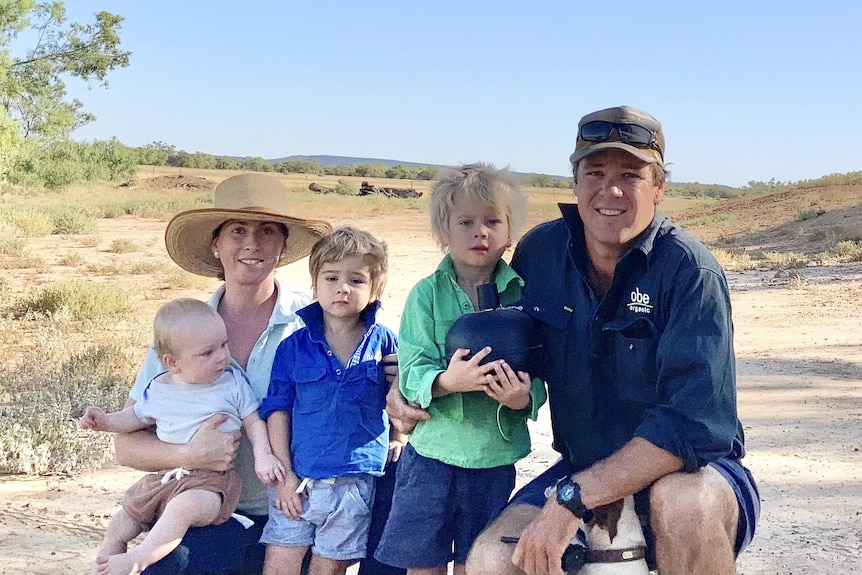 A young mother holding her baby with husband and two young boys in the outback.