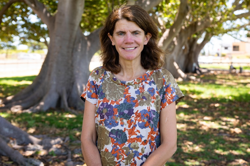 A woman standing under some trees.