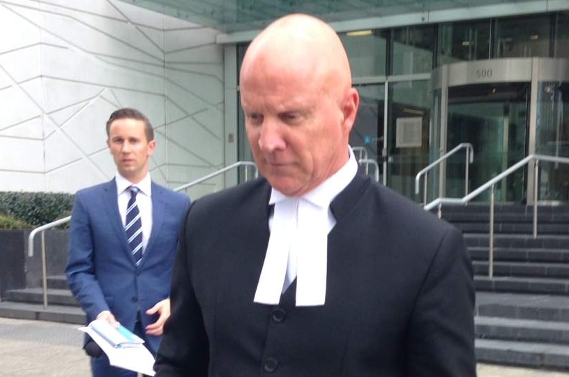 A lawyer walks with reporters outside the District Court building.